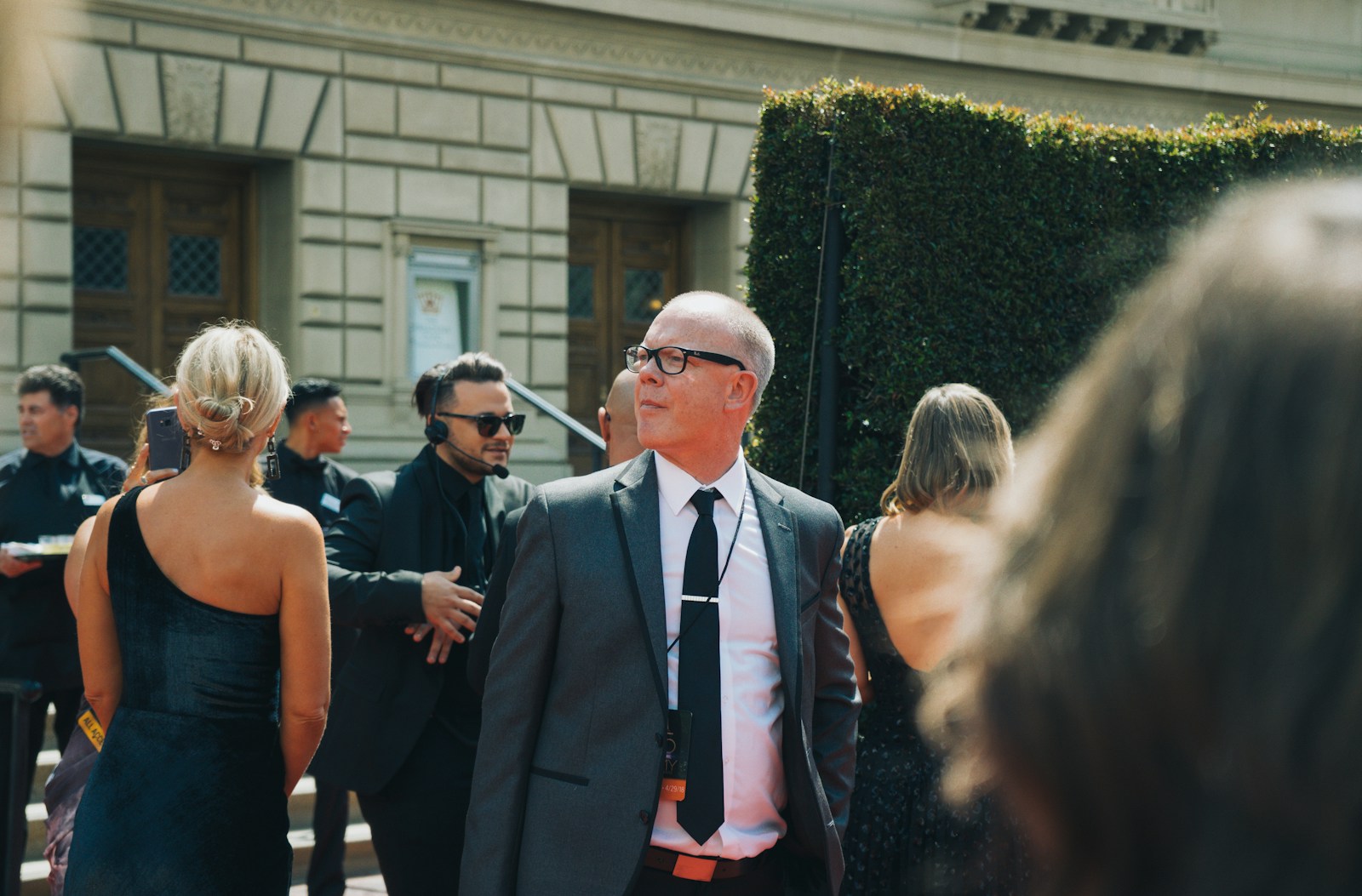 man in black suit standing beside woman in black sleeveless dress arriving from NY celebrity transportation